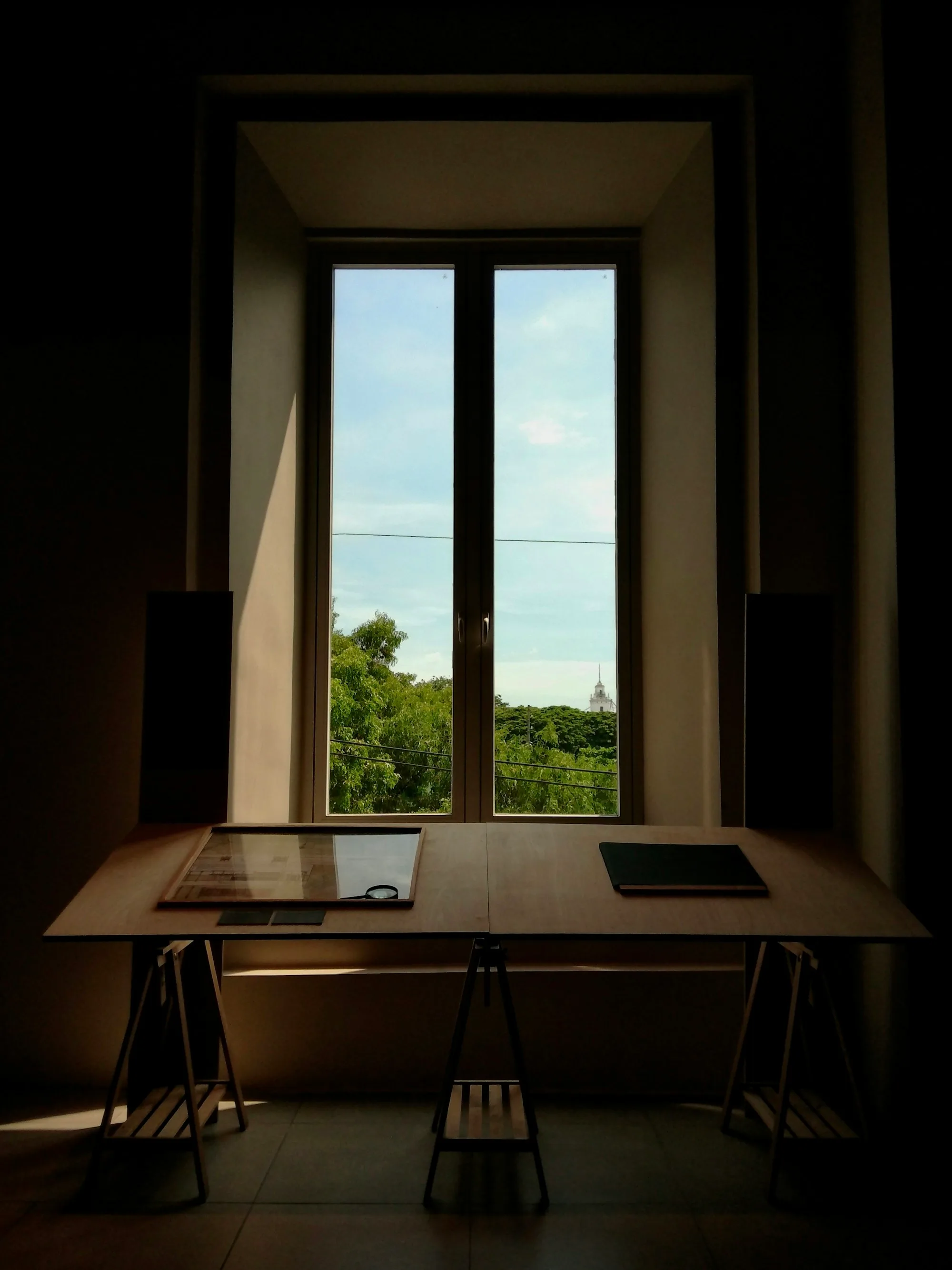 Mesa de trabalho em frente a uma janela com vista para árvores